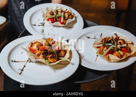 Flügel im Honig - Senf Soße auf knusprige Tortilla mit Gemüse und Kräutern. Stockfoto