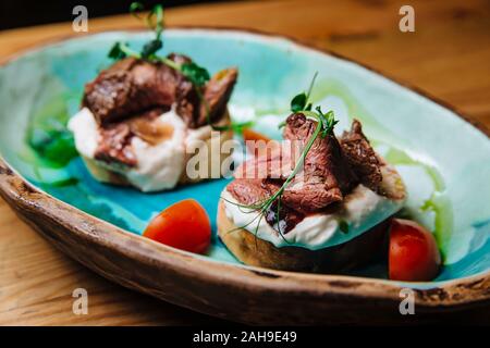 Bruschetta mit Roastbeef auf Zwiebel Brot medium gebratenes Roastbeef und saurer Sahne-Sauce. Leckere Snacks, Sandwiches. Stockfoto