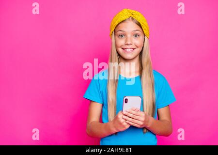 Portrait von Lustige funky Crazy cute Kind Positiv fröhliche kleine blogger Ihr Telefon verwenden, süchtig Social Network User tragen blaue Kleidung gelb headban Stockfoto