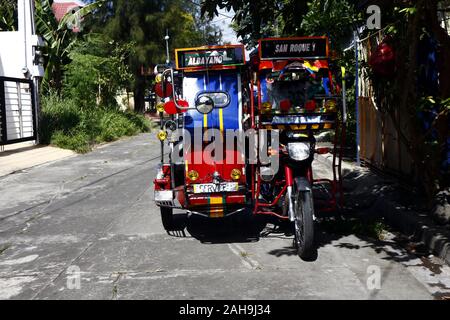 Antipolo City, Philippinen - Dezember 19, 2019: eingerichtet und farbenfroh Passagier Dreirad unter dem Schatten eines Baumes durch einen Bürgersteig geparkt. Stockfoto