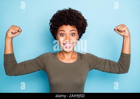 Portrait von überrascht verrückt Mulatte girl show Muskeln, die durch ihre Macht scream wow omg Verschleiß casual style Kleidung beeindruckt isoliert über blaue Farbe Hintergrund Stockfoto