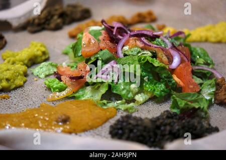 Eine Rolle der Injera Roll ist ein Sauerteig - auferstandenen Fladenbrot mit einer einzigartigen, leicht schwammig Textur mit traditionellen Äthiopischen Eintöpfe und Gemüse serviert. Stockfoto