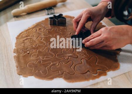 Nahaufnahme einer Frau Hand Lebkuchen Männer Cookies mit Metall Cutter. Vorbereitung auf Weihnachten handgefertigte Ingwer Cookies Stockfoto