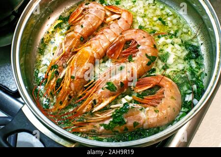 Große Langustinen mit Öl und Kräutern auf der Pfanne. Gebratene Riesengarnelen oder Tiger Garnelen mit grünen Kräutern. Stockfoto