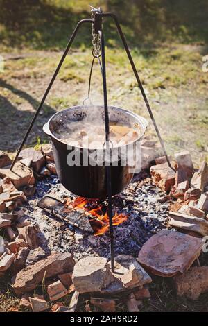 Kochen Abendessen in den großen Kessel auf Camping Feuer. Sonnigen Sommertag Stockfoto