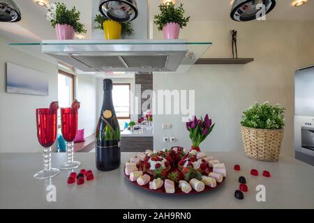 Köstliches Dessert. Flasche Champagner. Blumen. Paar Rotwein Gläser. Stockfoto