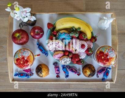 Romantische Komposition. Zwei Tassen, zwei Muffins, Kuchen, Donuts und Obst. Blick von oben. Stockfoto