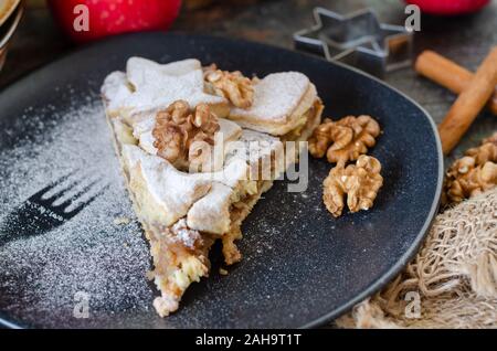 Scheibe der frisch gebackene hausgemachten Apfelkuchen und Walnüsse auf die schwarze Platte Stockfoto