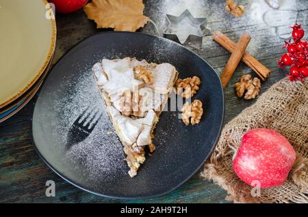 Scheibe der frisch gebackene hausgemachten Apfelkuchen und Walnüsse auf die schwarze Platte Stockfoto