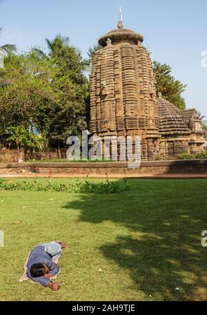 Bhubaneshwar, Orissa, Indien - Februar 2018: Ein Mann schläft in den grünen Gärten rund um den alten Mukteshwar Tempelkomplex. Stockfoto