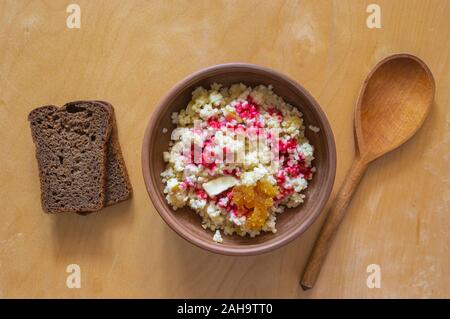 Ansicht von oben auf einem Steingut Schale mit Hirse Haferflocken in Milch mit Apfelstückchen gekocht und gewürzt mit frischen Himbeeren Orangensaft und Honig Stockfoto
