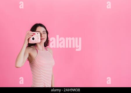 Ein junges Mädchen in einem rosa gestreiftes Kleid hält eine Kamera in ihren Händen Stockfoto