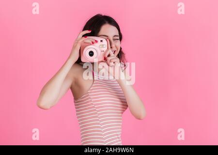 Ein junges Mädchen in einem rosa gestreiftes Kleid hält eine Kamera in ihren Händen Stockfoto