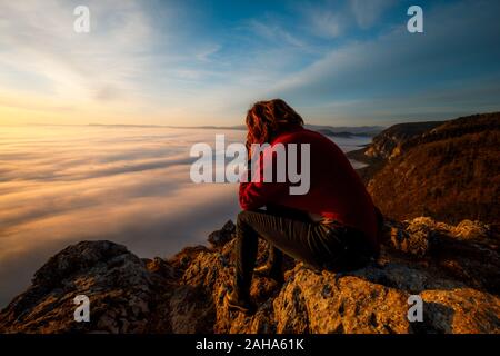 Glückliche Frau Touristen sitzen auf dem Gipfel des Berges und auf der schönen Nebel betrachten. Konzept der Freiheit. Stockfoto