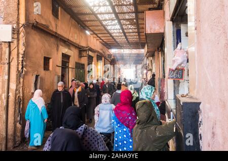 Belebte enge Straße mit Menschen zu Fuß und Einkaufen in Medina von Marrakesch, Marokko. Stockfoto