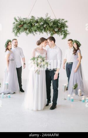 Wunderschöne Braut mit Pfingstrose Bouquet und stilvolle Bräutigam mit Brautjungfern und Trauzeugen am Hochzeitstag posieren. luxus Hochzeit paar Spaß mit Freund Stockfoto