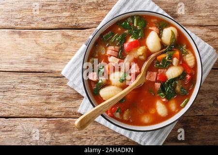 Traditionelles Rezept für Gnocchi mit Suppe, Würstchen, Tomaten, Spinat und Gemüse close-up in einer Schüssel auf den Tisch. Horizontal oben Ansicht von oben Stockfoto