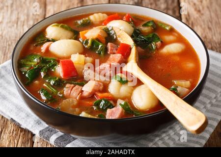 Traditionelles Rezept für Gnocchi mit Suppe, Würstchen, Tomaten, Spinat und Gemüse close-up in einer Schüssel auf dem Tisch. Horizontale Stockfoto