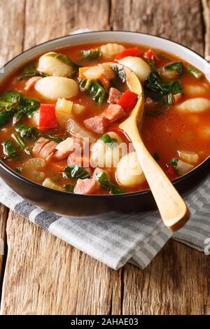 Leckere Tomatensuppe mit Gnocchi, Wurst und Gemüse close-up in einer Schüssel auf dem Tisch. Vertikale Stockfoto