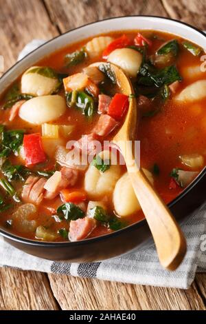 Italienische Tomatensuppe mit Gnocchi, Wurst und Gemüse close-up in einer Schüssel auf dem Tisch. Vertikale Stockfoto