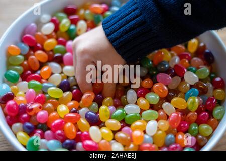 Eines Kindes Hand eintauchen in eine Schüssel voller Geleebonbons Stockfoto