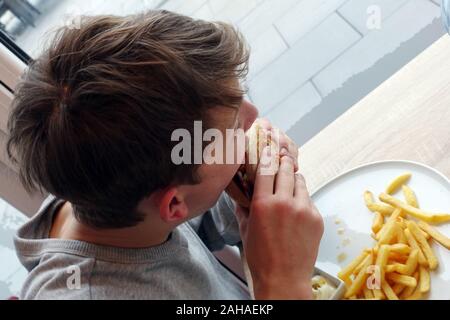 27.01.2018, Berlin, Berlin, Deutschland - Junge isst einen Hamburger mit Pommes frites. 00 S180127 D037 CAROEX.JPG [MODEL RELEASE: JA PROPERTY RELEASE: NEIN (c) Stockfoto