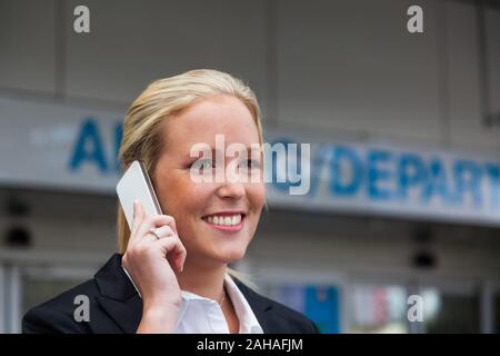 Eine Geschäftsfrau telefoniert mit ihrem Handy am Flughafen. Roaminggebühren bei Smartphones im Ausland, HERR: JA Stockfoto