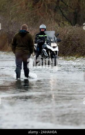 Ein Motorradfahrer versucht eine überflutete Straße in der Nähe von Harbridge, 2,5 km nördlich von Ringwood in Hampshire zu fahren, nach dem Fluss Avon seine Banken platzen. Stockfoto