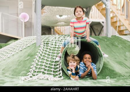 Fröhlich und freundlich Interkulturelle kleine Kinder gemeinsam Spaß am Spielplatz