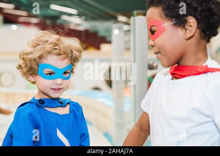 Zwei kleine Jungs tragen Kostüme von Superhelden, die zusammen spielen im Kindergarten Stockfoto