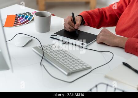 Die Hände der jungen männlichen Freelancer mit Stift Retuschieren von Fotos im Graphics Tablet Stockfoto