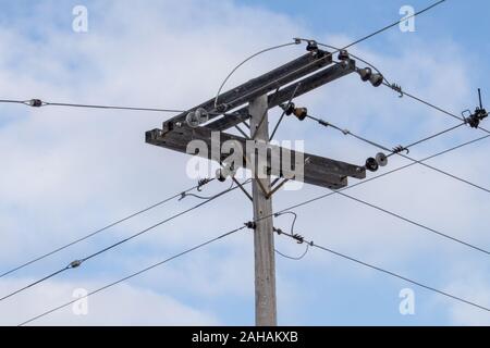 Eine ländliche Kreuzung der elektrischen Leitungen erhöht wird durch eine hölzerne Stange. Die Anschlüsse der Leitungen Strom in alle Richtungen übertragen, die die Stockfoto