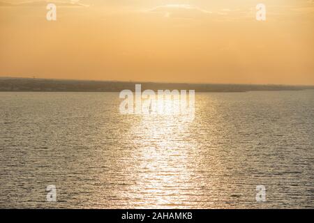 Segeln Bei Sonnenuntergang. Saisonale Bilder mit glänzendem Meer und segelboot über bewölktem Himmel und Sonne bei Sonnenuntergang Apulien Küste, Italien. Stockfoto