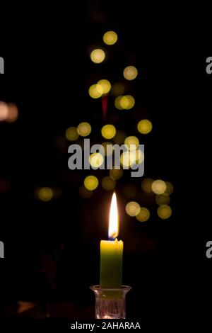 Eine einzige Kerze leuchtet vor einem unscharf Weihnachtsbaum Stockfoto