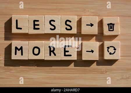 Weniger Müll, mehr Recycling, in der Wörter und Symbole in 3d Holz- alphabet Blöcke auf Bambus Holz Hintergrund Stockfoto