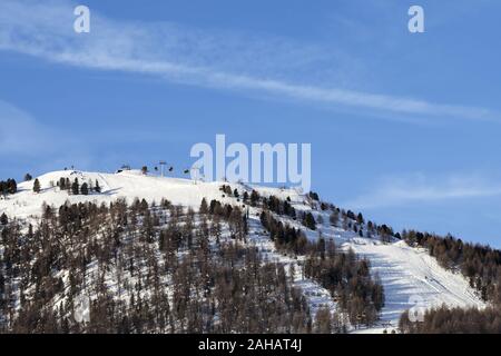 Top der verschneiten Piste mit Ski-lifts, Spuren und Wald im Winter Berge am sonnigen Morgen. Italienische Alpen. Livigno, Region Lombardei, Italien, Stockfoto