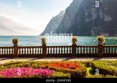 Garda See Promenade mit bunten Blumenbeeten mit wachsenden und blühenden Pflanzen, classic Stone Fence am Rande mit Blumentöpfen mit blühenden fl gebaut Stockfoto