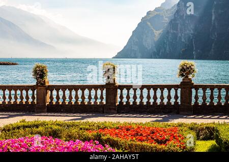 Garda See Promenade mit bunten Blumenbeeten mit wachsenden und blühenden Pflanzen, classic Stone Fence am Rande mit Blumentöpfen mit blühenden fl gebaut Stockfoto