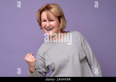 Senior kaukasischen weibliche Sieger heben den Arm, ballte die Faust und rief mit Freude und Aufregung. Sieg, Erfolg und Leistung Konzept. Studio sho Stockfoto
