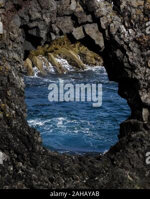 Loch in der isländischen schwarze Lava Rock Formation mit Atlantik im Hintergrund. Schuss in der Nähe von Vik, Island auf dem schönen, sonnigen Sommertag. Stockfoto