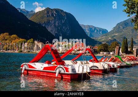 Riva del Garda, Italien - 12 September 2019: Schöne Riva del Garda Stadtbild mit leuchtend roten Tretboote in einer Reihe geparkt am Strand und Stadt surr Stockfoto