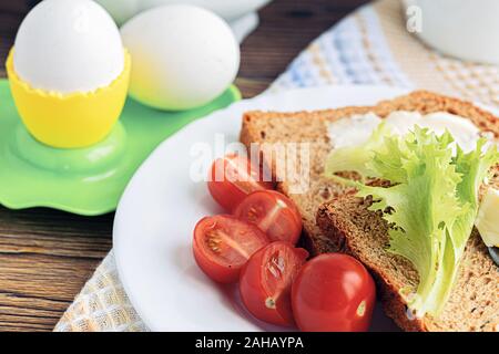 Frühstück im Landhausstil: Scheiben Getreidebrot mit Salat, Tomaten und Frischkäse. Stockfoto