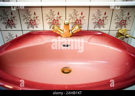 Vintage pink gold Waschbecken mit Wasserhahn und Blumenmuster Fliesen- Wand im Bad Stockfoto