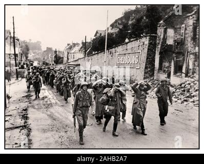 2. Weltkrieg 1944. Juni deutsche Wehrmachtgefangene nahmen und übergaben Soldaten mit Händen an Köpfen nach der Operation Overlord D-Day Offensive, die mit amerikanischen alliierten Truppen durch eine Straße in Cherbourg marschierte, WW2. Weltkrieg Frankreich Deutschland kapitulierte Hände an Köpfen Stockfoto