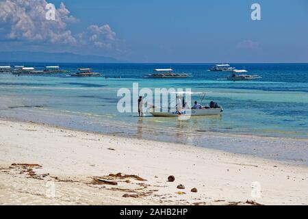 Mann Liegeplatz Boot mit Menschen an Bord in Phillippinische Strand Stockfoto