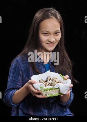 Portrait eines Mädchens mit Wachteleier auf schwarzem Hintergrund Stockfoto