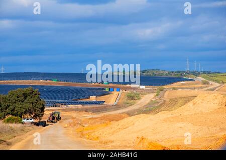 Gelb mit blauen Solarzellen auf der linken Seite große, alte fieldengine unter den grünen Baum. Blauen bewölkten Himmel. Sevilla, Spanien Stockfoto