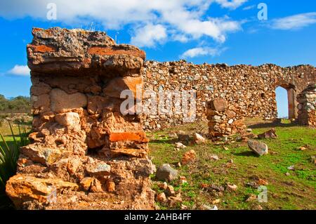 In der Nähe der alten Stein ruiniert Wand mit gewölbten Tür auf der grünen Wiese, blauer Himmel mit weißen Wolken. Sonnigen Herbsttag in Sevilla, Spanien Stockfoto