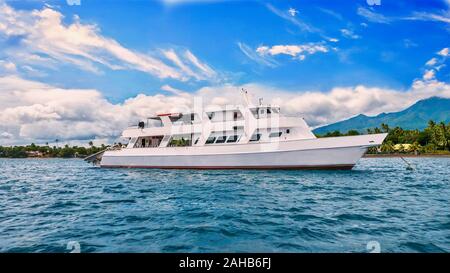 Eine schöne private Motoryacht, die auch als Tauchsafari Tauchboot verwendet wird, ist vor einer tropischen Insel in den Philippinen verankert. Stockfoto