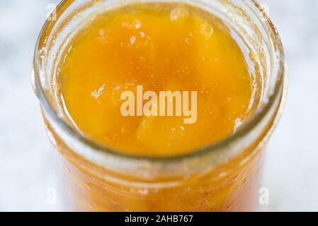 Hausgemachte mango Marmelade im Glas auf weißem Hintergrund. Eine Nahaufnahme, selektiver Fokus, essen Hintergrund. Kopieren Sie Platz für ein Logo oder Text Stockfoto